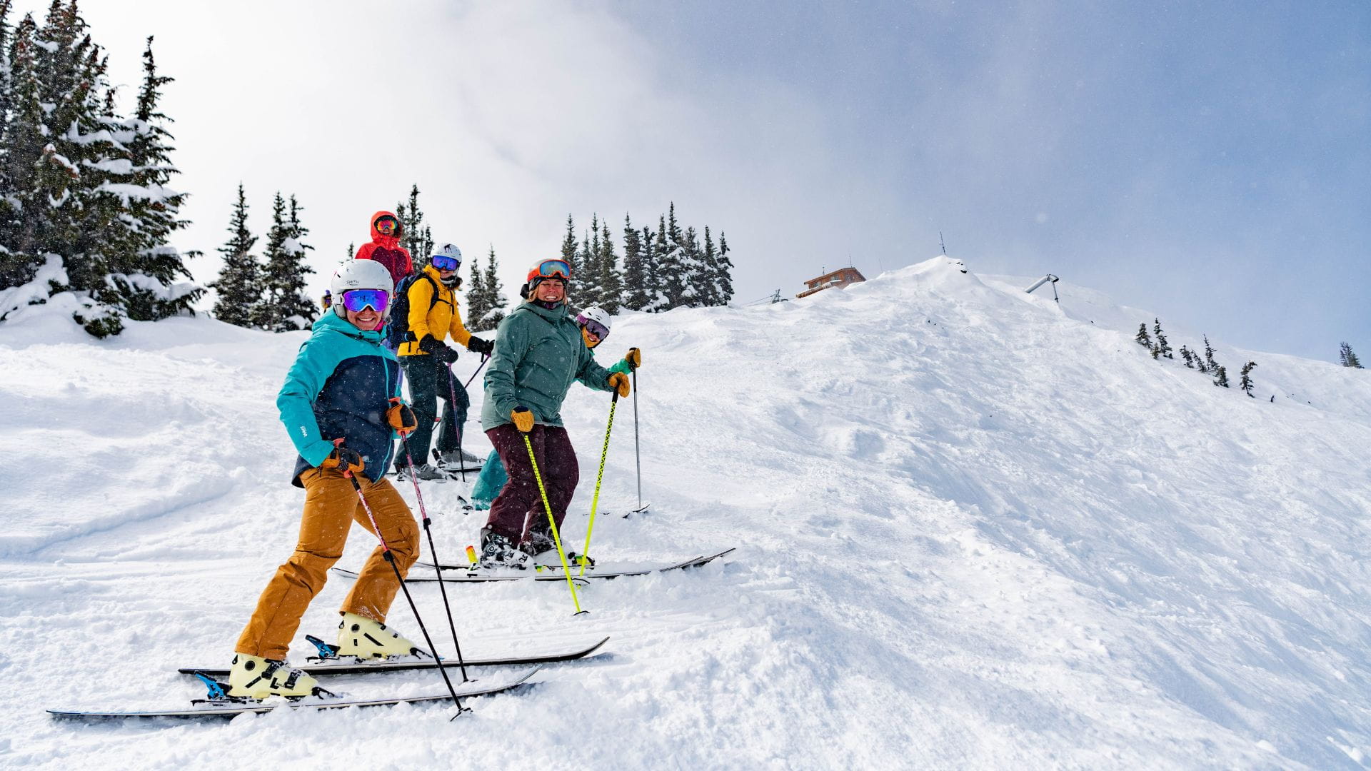 Group of women skiers pose for a photo at the top of a ski run. 