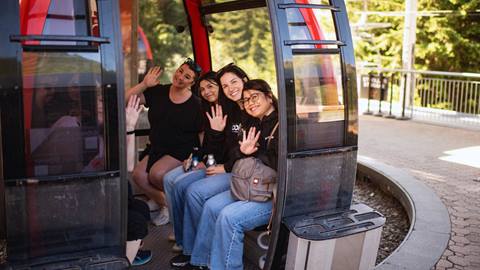A group of women waves from a gondola car at the base of Crystal Mountain