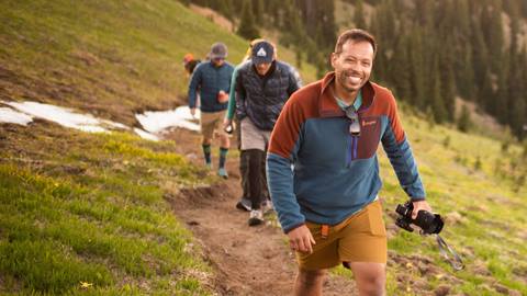 Three men walk on a Crystal Mountain ridge line path.