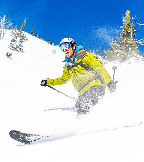 A skier carving through fresh powder on a sunny day at Crystal Mountain Resort