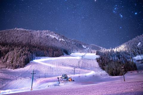 Image of ski hill at night with stars in the background. 