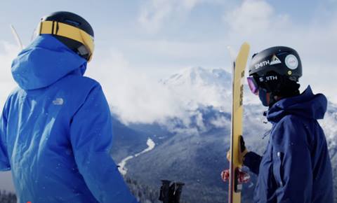 A ski instructor and their student look across the valley, ready to tackle the terrain. 