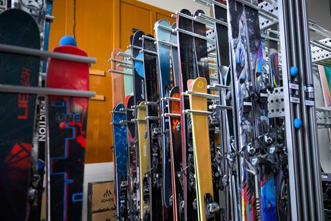 Assorted demo skis hang on a rack.
