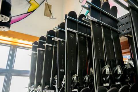 Black Rossignol skis hang on a rack in a rental shop. 