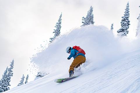 Snowboarder glides on a powder run.