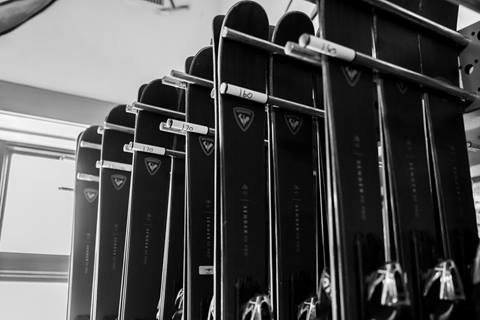 Black Rossignol skis hang on a rack.