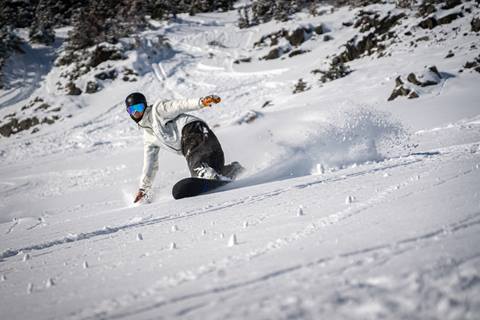 Snowboarder carves on a powder day. 