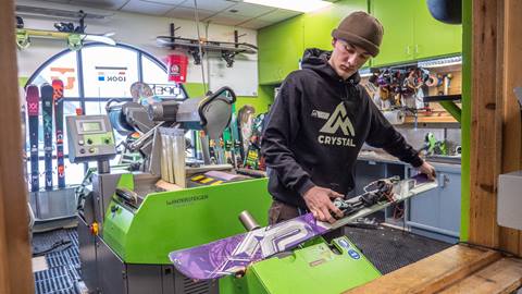 A technician tuning a ski on a service machine in the tune shop at Crystal Mountain Resort